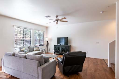 A living room with a grey couch, a black chair, and a television.