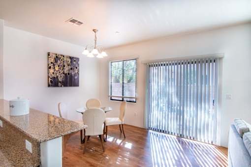 A kitchen with a granite counter top and a dining table with chairs.