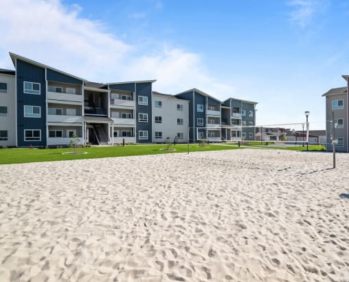 a beach with sand in front of an apartment building