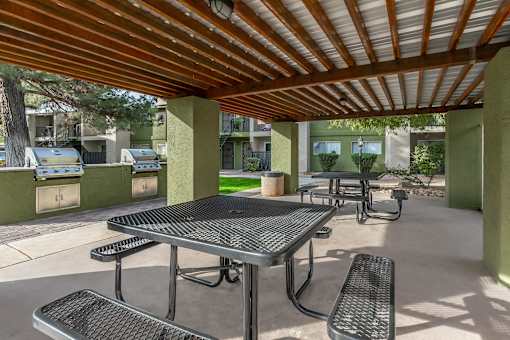 A patio with a table and chairs under a roof.
