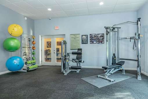 A gym with a variety of equipment including a leg press machine, a bench press, and a squat rack.