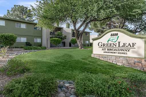 A sign for Green Leaf Apartments is in front of a building.