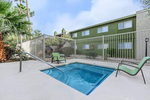 A pool surrounded by a fence and chairs.
