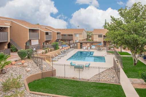 A swimming pool surrounded by a fence and chairs.