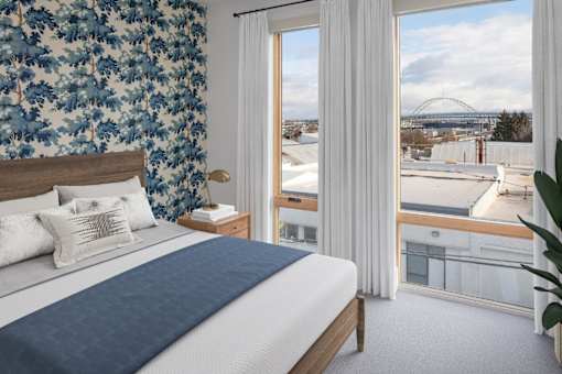 A bedroom with a large bed and a view of a bridge.