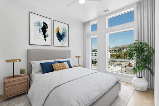 A bedroom with a large bed, two lamps, and two framed artworks on the wall.