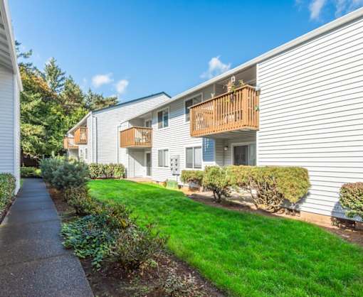 Beautiful landscaping and green grass along private balconies at Heron Hills apartments in Gresham Oregon.
