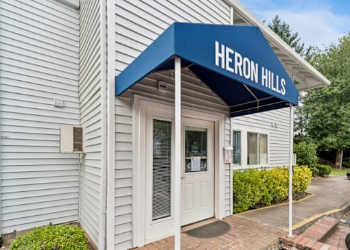 A building with a blue awning that says Heron Hills.