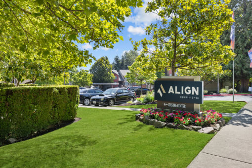 a sign on a lawn with cars in the background