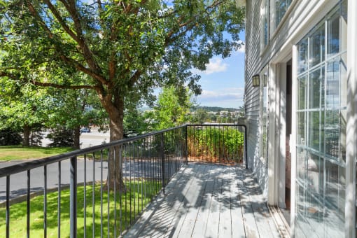 the view from the deck of a home with a large tree and a balcony