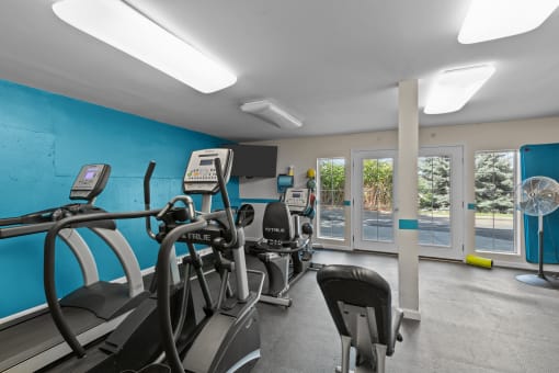 a room filled with lots of cardio equipment and a wall of windows