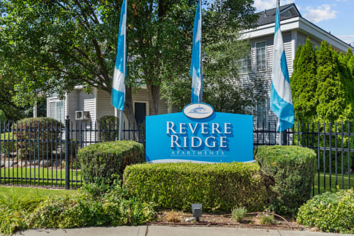 a blue reverse ridge apartments sign in front of a black fence