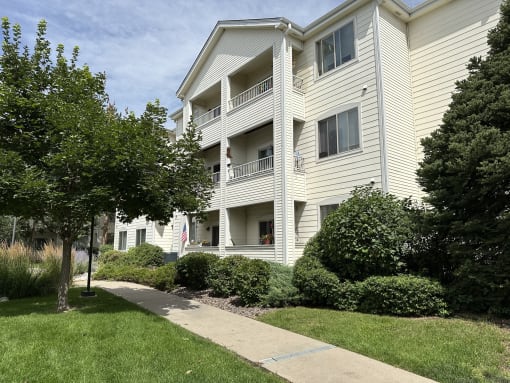 a white apartment building with a sidewalk in front of it