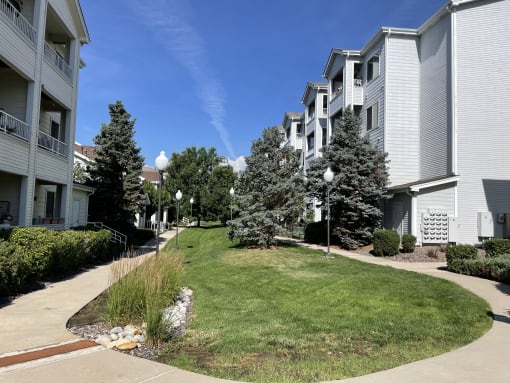 an apartment building with a lawn and trees in front of it