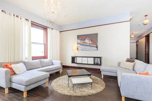 A living room with a grey couch, a coffee table, and a framed picture on the wall.