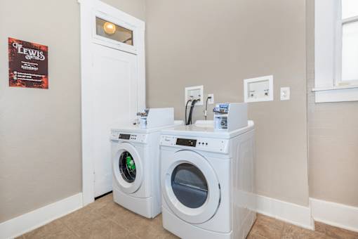 Two white front loading washing machines in a laundry room.
