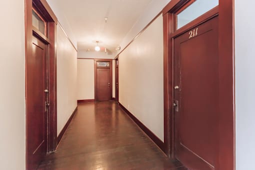 A long hallway with doors on both sides and a door at the end.