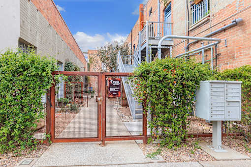A gate with a mailbox on the side of a brick building.