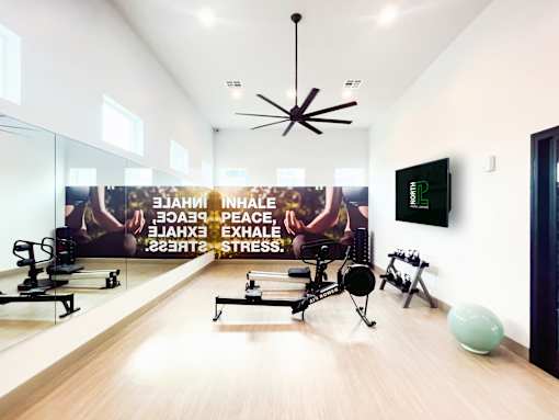 A gym room with exercise equipment and a wall mural promoting inhalation, exhalation, peace, and stress relief.