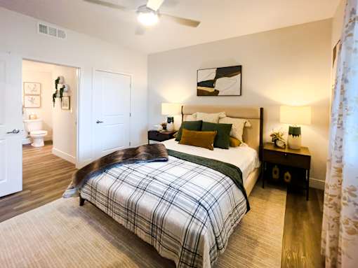 A bedroom with a bed, nightstand, and a ceiling fan.