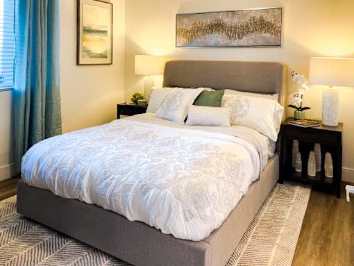 A bed with a white comforter and a grey headboard is in the image.