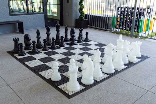A giant chess set with black and white pieces on a black and white checkered board.