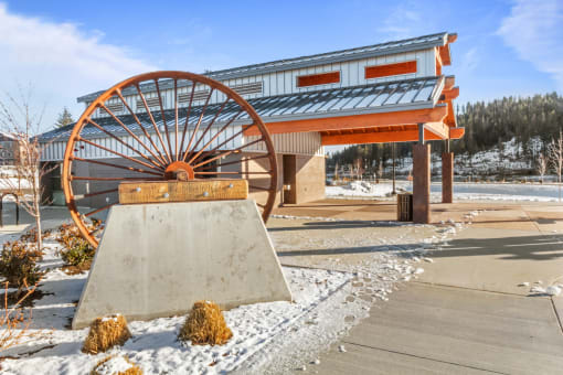 a large wheel sits in front of a building with snow on the ground