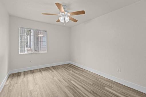 A room with a ceiling fan and a window with bars.