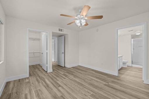 A room with a ceiling fan and wood flooring.