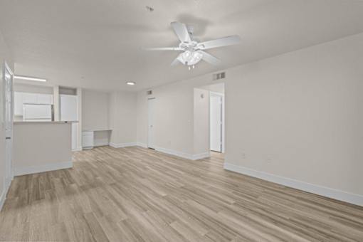 A room with a ceiling fan and wooden flooring.