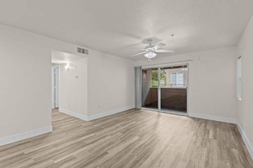 A room with a ceiling fan and sliding glass doors.