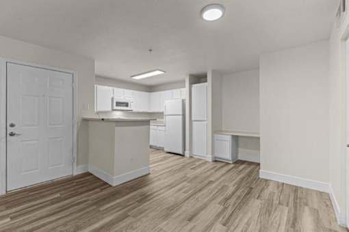 A kitchen with white cabinets and a wooden floor.