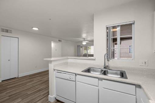 A kitchen with white cabinets and a window.