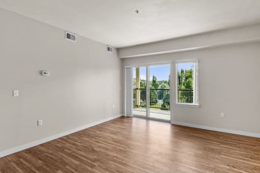 a bedroom with hardwood floors and a sliding glass door leading to a balcony