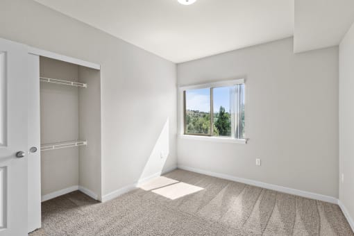 an empty bedroom with a large window and a closet