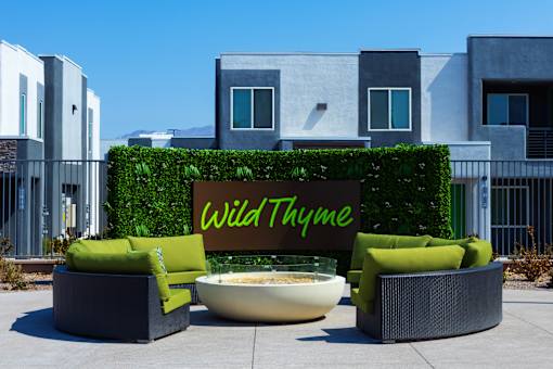A sign that says Wild Thyme is in front of a green hedge.