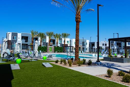 A palm tree stands in front of a row of houses with a pool in the foreground.