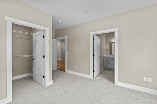 a bedroom with two closets and a bathroom in the background
