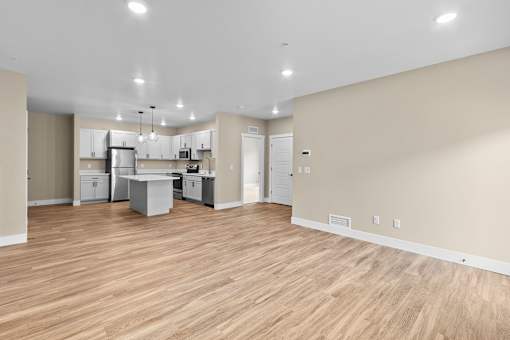 a spacious living room with a kitchen in the background