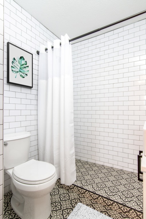 a bathroom with white subway tile and a white shower curtain