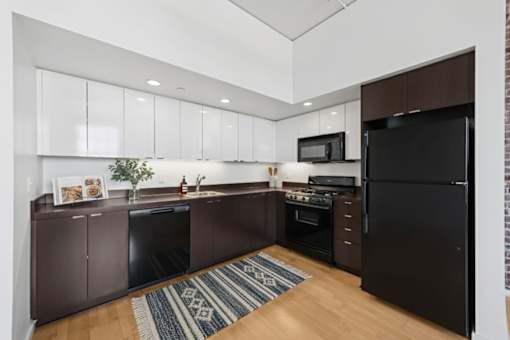 A kitchen with brown cabinets and a black refrigerator.