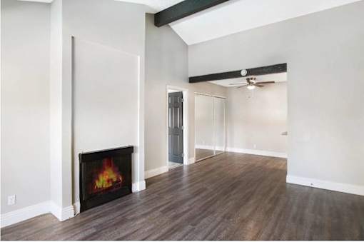 A room with a fireplace and wood flooring.