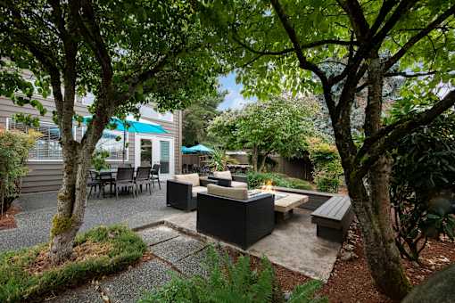 A modern outdoor seating area with a black sofa and table.