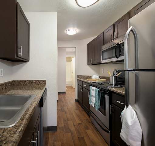 A kitchen with black appliances and brown cabinets.