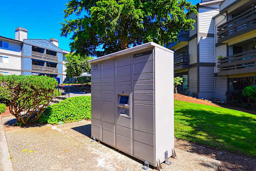 A grey portable toilet is placed on a concrete slab in a grassy area.