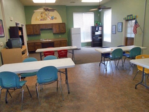 a classroom with tables and chairs and a kitchen