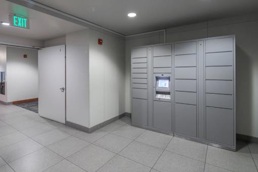 A row of grey lockers with a green exit sign above them.