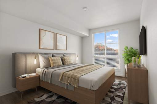 A bedroom with a large bed, a nightstand with a lamp, and a TV on the wall.