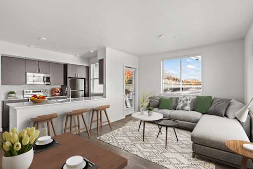 A modern kitchen with a breakfast bar and a living room with a grey couch.