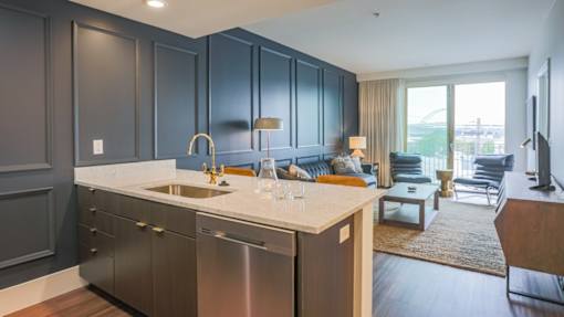 A modern kitchen with dark grey cabinets and stainless steel appliances.